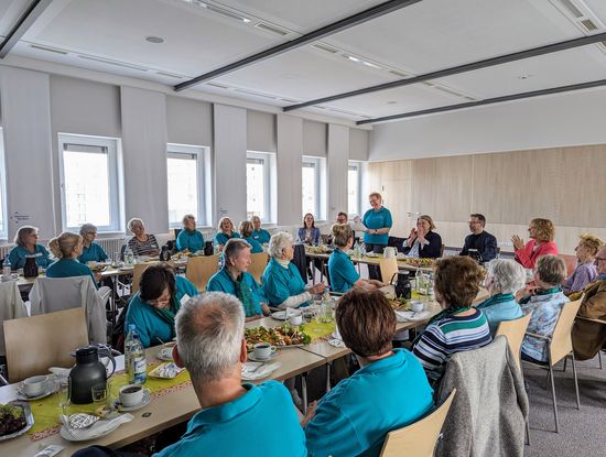 Fröhliches Beisammensein: Helga Bathe begrüßt die Gäste und die Grünen Damen und Herren zur Jubiläumsfeier (Foto: Oberhavel Kliniken GmbH).